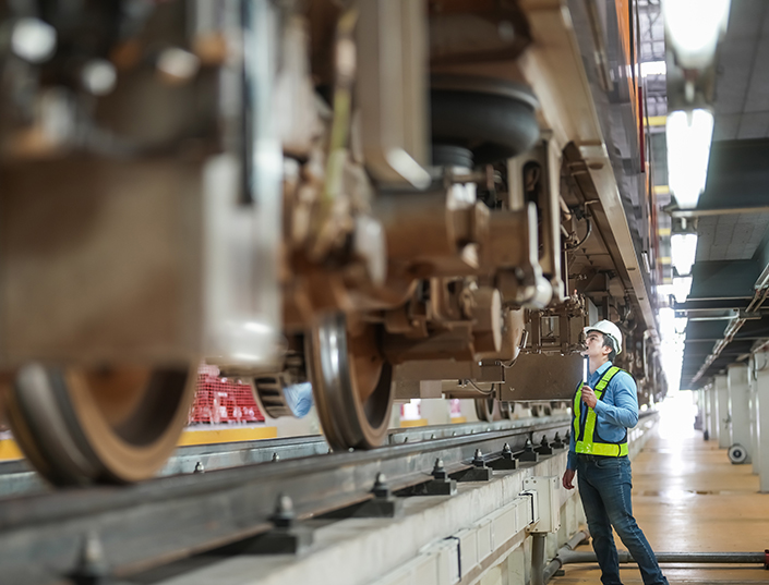 An engineer inspects the tracks and train components.